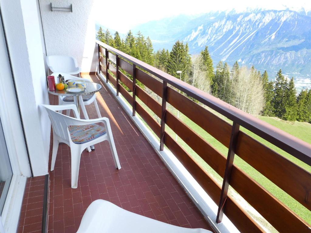 a balcony with a table and a chair and mountains at Apartment Clairière des Barzettes B16 by Interhome in Crans-Montana