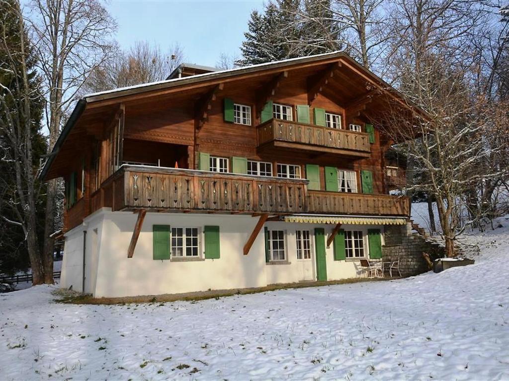 een groot houten huis met een balkon in de sneeuw bij Apartment Les Erables- Chalet by Interhome in Gstaad