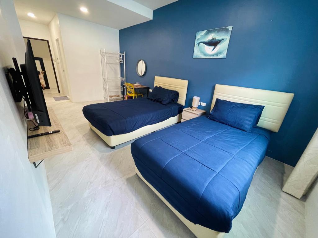Blue whale Hostel & Café في باتايا سنترال: سريرين في غرفة بجدران زرقاء