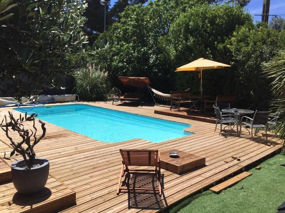 a wooden deck with a pool and a table and chairs at Superbe villa près du Cap d'Agde in Florensac