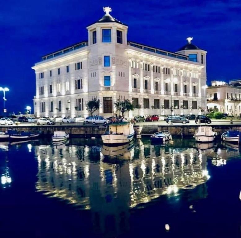 a large white building with boats in the water at Casetta BLU in Siracusa