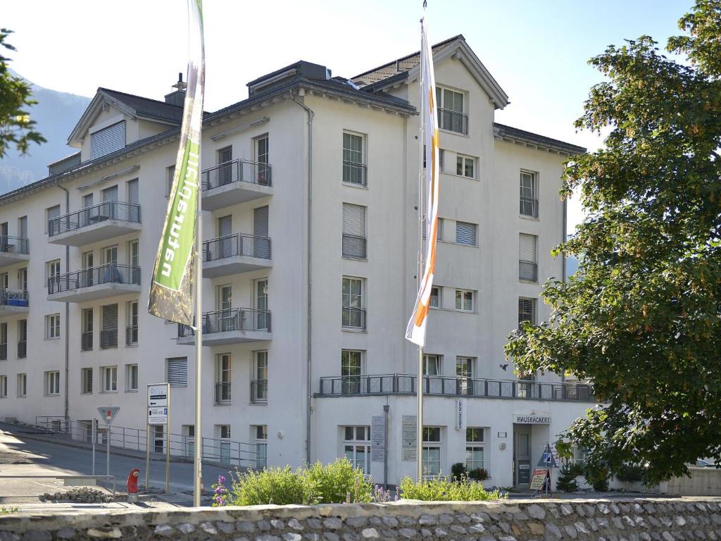 ein großes weißes Gebäude mit Flaggen davor in der Unterkunft Apartment Moser by Interhome in Churwalden