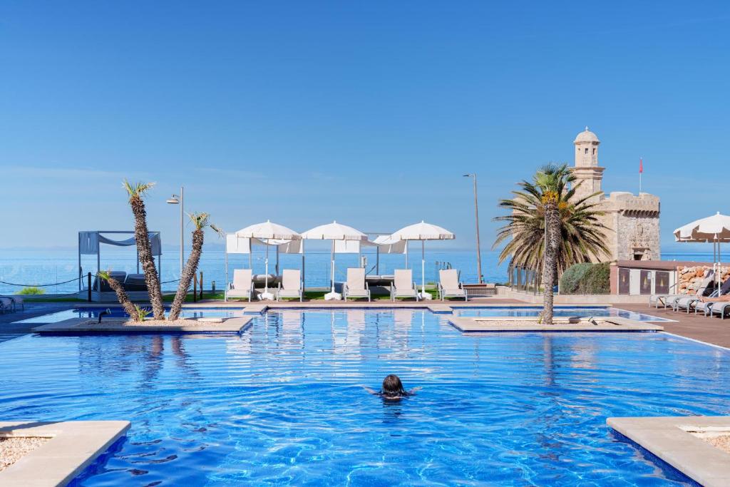 una persona nadando en una piscina en un complejo en Aparthotel Ferrer Skyline en Ciutadella