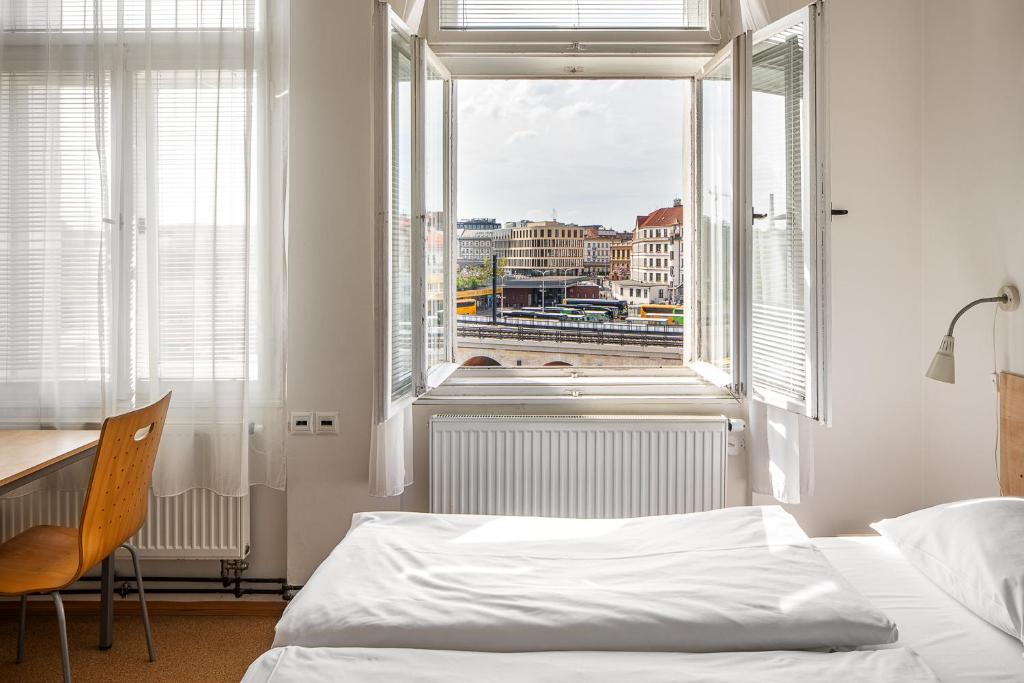 a bedroom with a bed and a desk and a window at Drunken Monkey Hostel in Prague