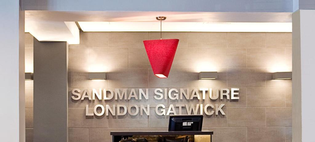 una luce rossa appesa a un cartello su un muro di Sandman Signature London Gatwick Hotel a Crawley