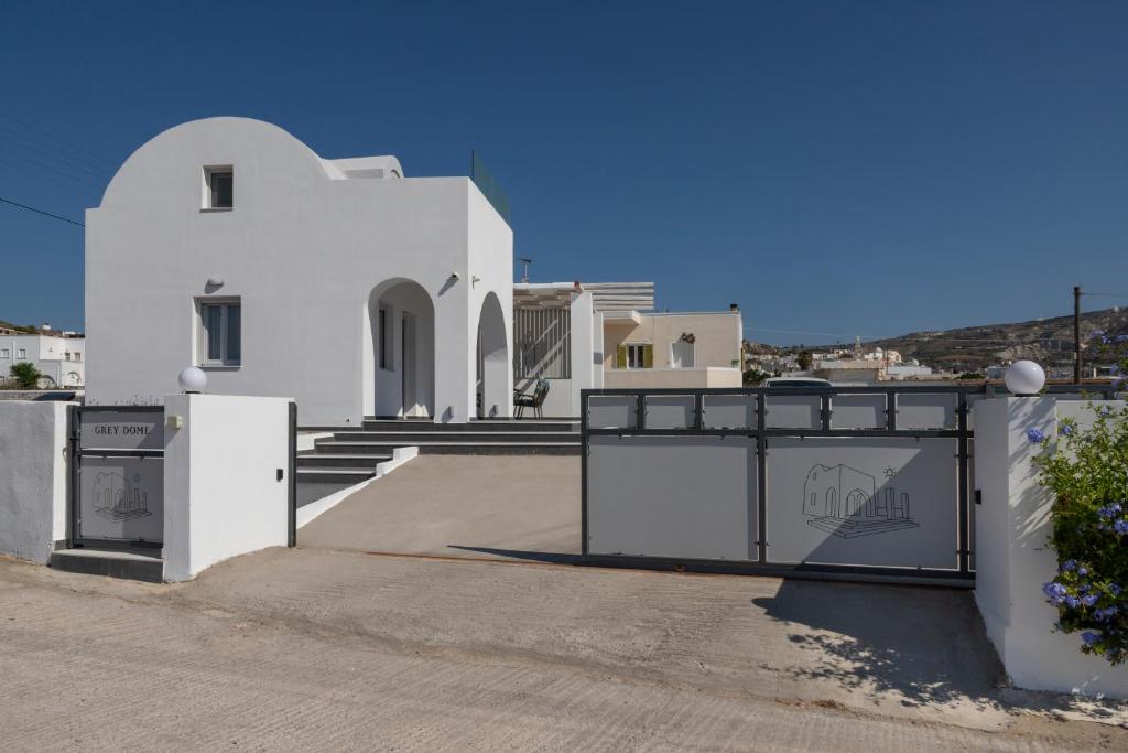 a white house with a gate in front of it at GREY DOME SANTORINI in Emboríon