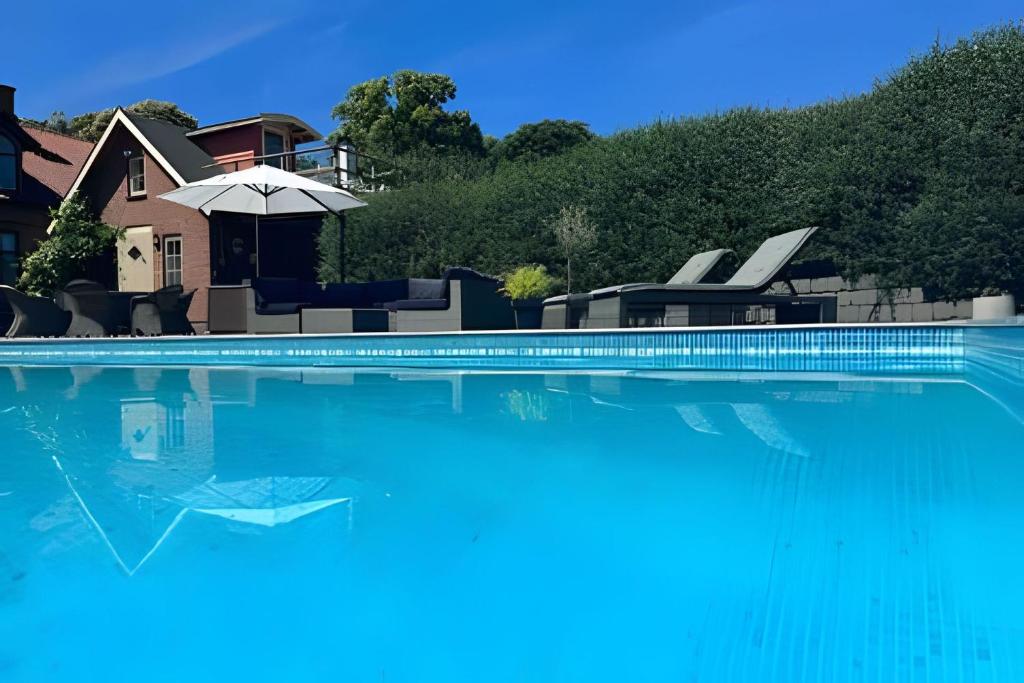 een groot zwembad met een huis en een parasol bij Vingårdens Bed & Breakfast in Helsingborg