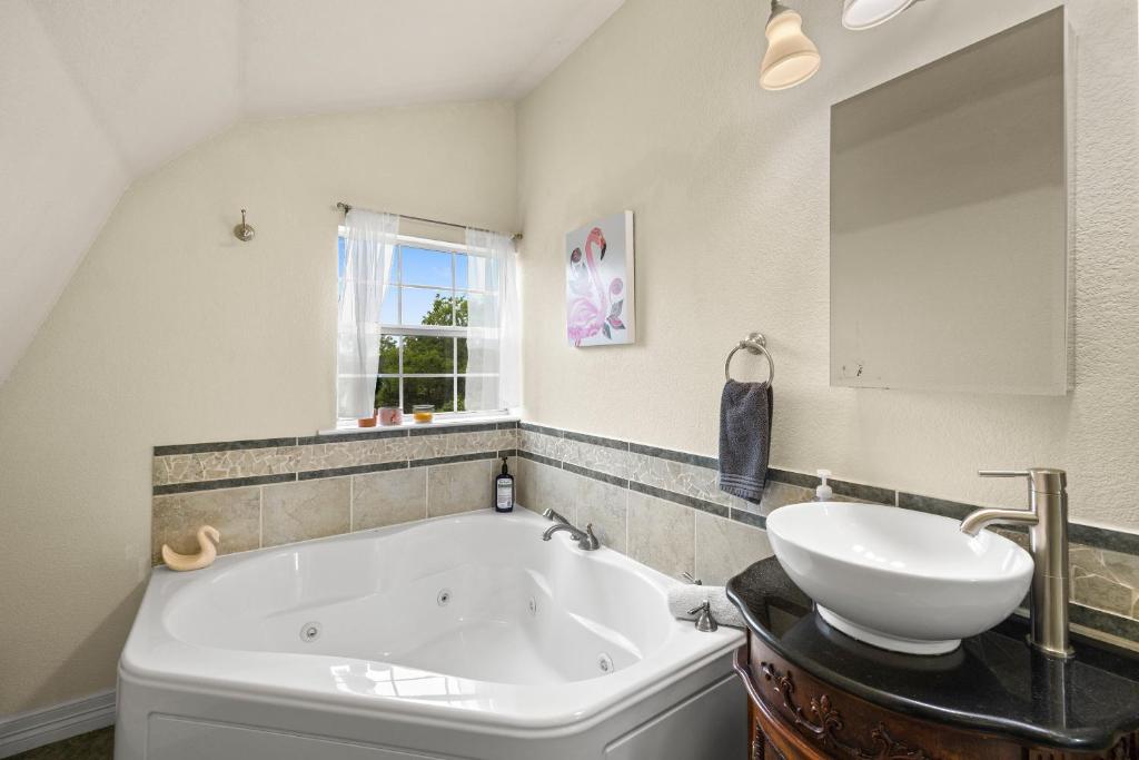 a bathroom with a tub and a sink and a mirror at Entire 2br 2ba hilltop view home Sleeps 8 pets 4 acres Jacuzzi Central AC Kingbeds Free Wifi-Parking Kitchen WasherDryer Starry Terrace Two Sunset Dining Patios Grill Stovetop Oven Fridge OnsiteWoodedHiking Wildlife CoveredPatio4pets & Birds Singing! in Marble Falls