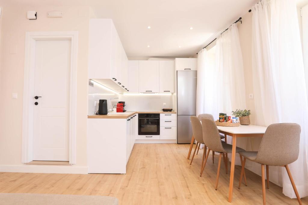 uma cozinha com armários brancos e uma mesa e cadeiras em Patras Luxury Apartment em Corfu Town