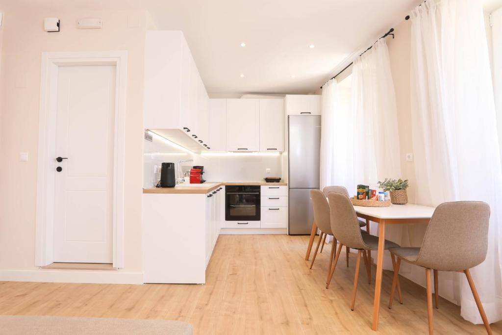 a kitchen with white cabinets and a table and chairs at Patras Luxury Apartment in Corfu Town