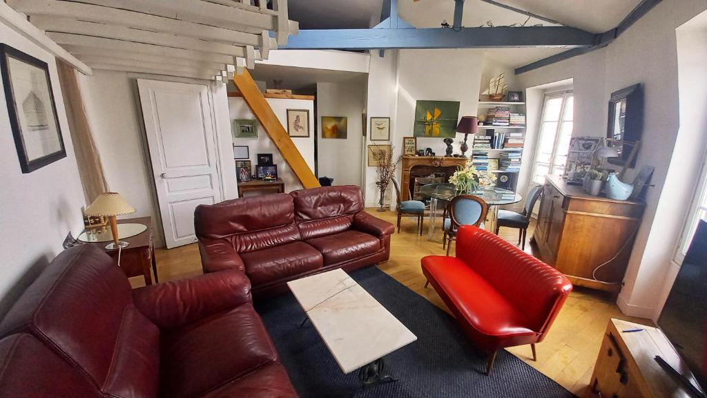 - un salon avec un canapé en cuir et des fauteuils rouges dans l'établissement Le 122 aux Batignolles, à Paris