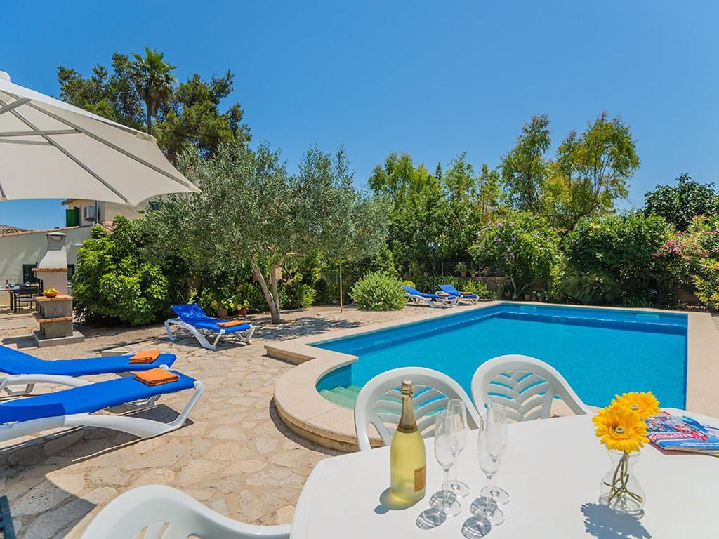 a swimming pool with a table and chairs and a bottle of wine at Holiday Home Cuxach d'en Joan by Interhome in Pollença