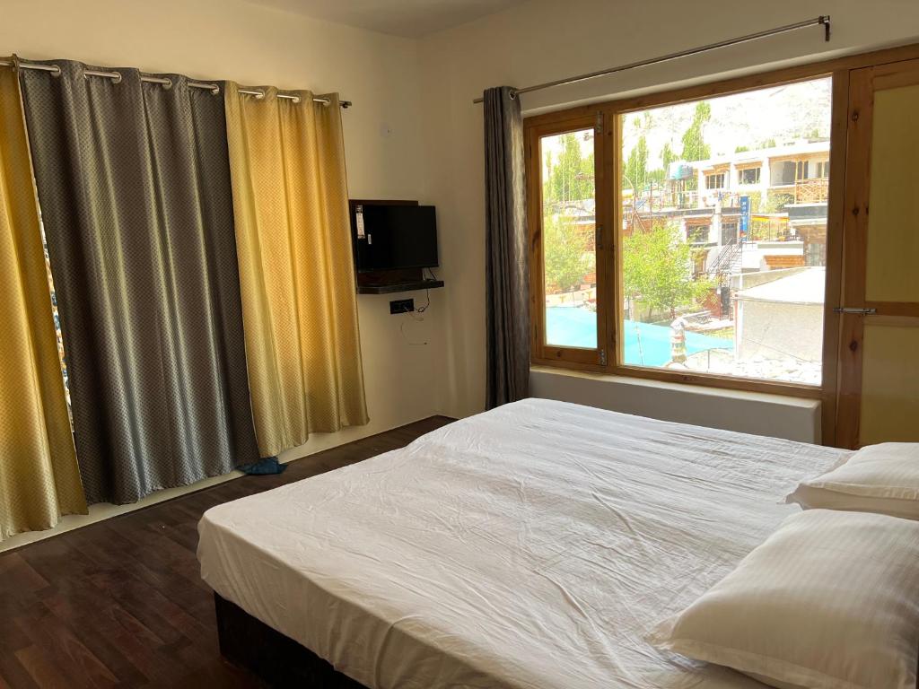 a bedroom with a large bed and a window at De katong in Leh