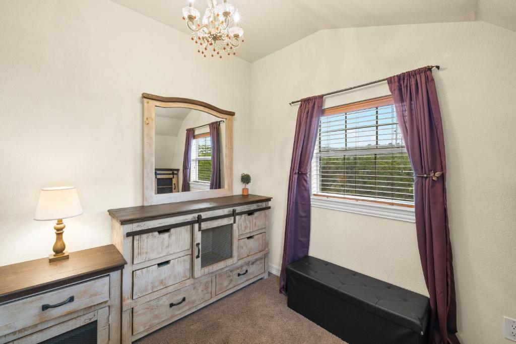 a room with a mirror and a dresser with a television at Entire 2br 2ba hilltop view home Sleeps 8 pets 4 acres Jacuzzi Central AC Kingbeds Free Wifi-Parking Kitchen WasherDryer Starry Terrace Two Sunset Dining Patios Grill Stovetop Oven Fridge OnsiteWoodedHiking Wildlife CoveredPatio4pets & Birds Singing! in Marble Falls