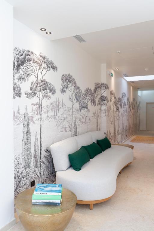 a white couch in a room with a mural of trees at La Garoupe-Gardiole in Antibes