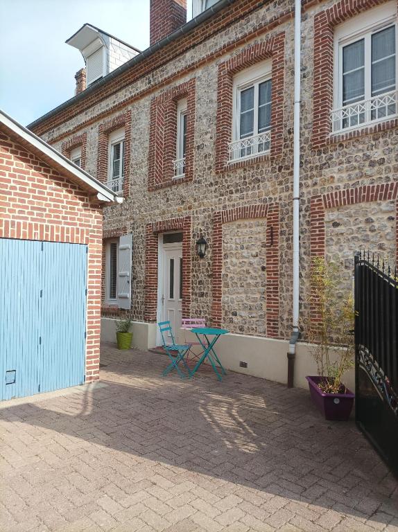 un bâtiment en briques avec une porte bleue et une clôture dans l'établissement Gite à Yport, à Yport