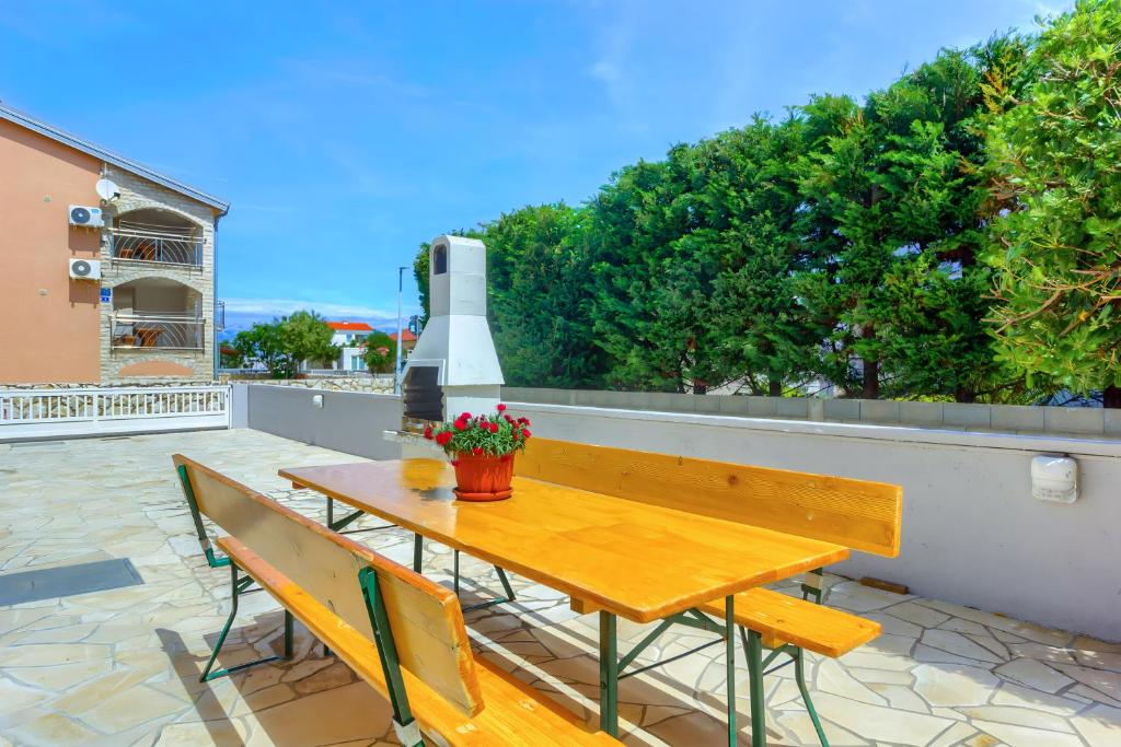 drewniany stół i ławka na patio w obiekcie Apartment House Virić w mieście Vir