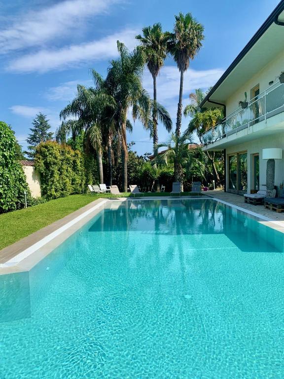 a swimming pool in front of a house with palm trees at Ara Town House in San Giovanni la Punta
