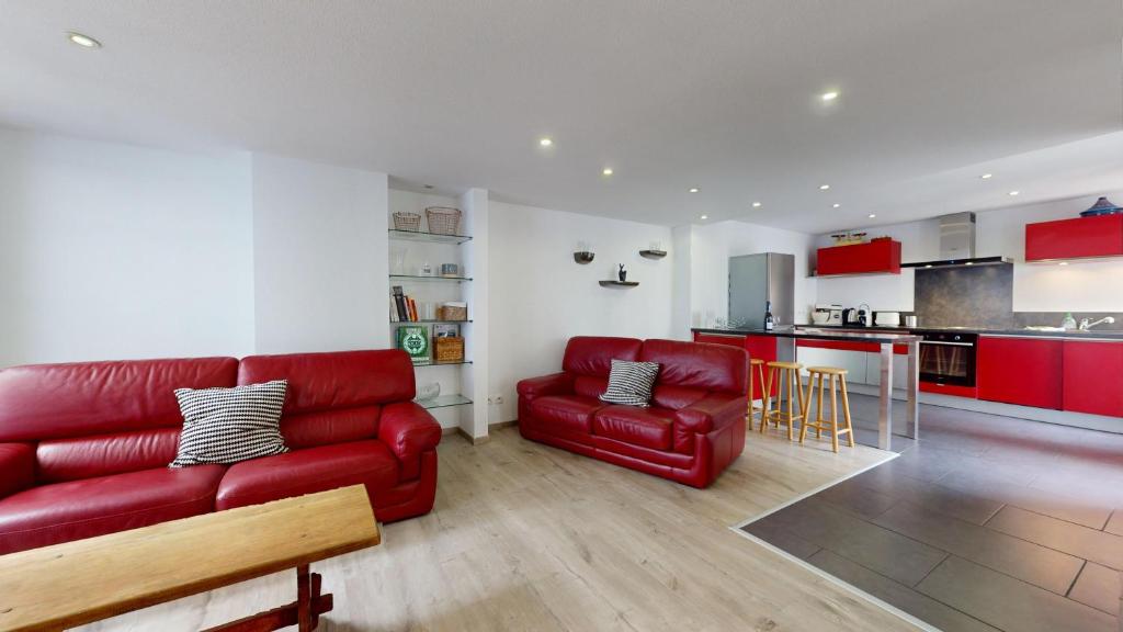 un salon avec un canapé rouge et une cuisine dans l'établissement Le Roesselmann 1 parking, à Colmar