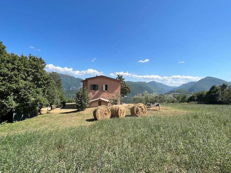 un campo con fardos de heno delante de una casa en Casa degli uccellini - Cerreto di Spoleto, en Cerreto di Spoleto
