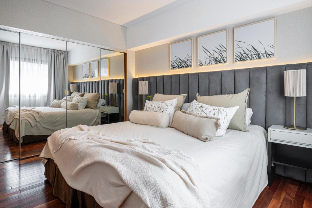 a bedroom with a large white bed and mirrors at Argenta Tower Hotel & Suites in Buenos Aires