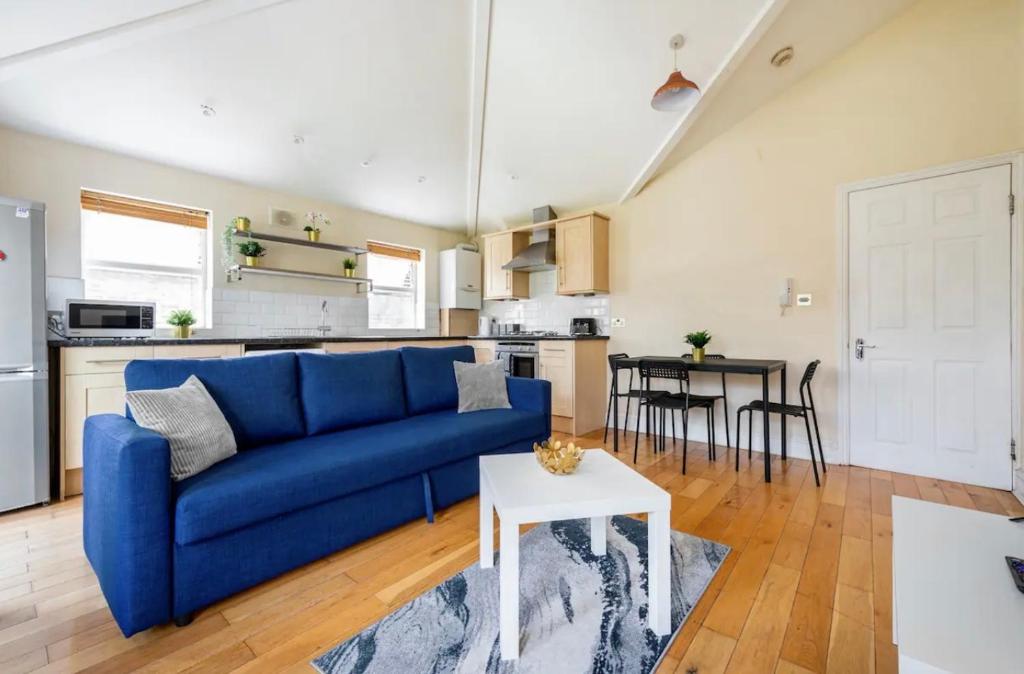 a living room with a blue couch and a kitchen at Lovely 3-bed 20 minutes to Central London in London