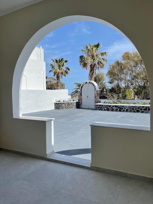 an archway in a building with a gate and palm trees at Sklavadi Vineyard House in Kamari