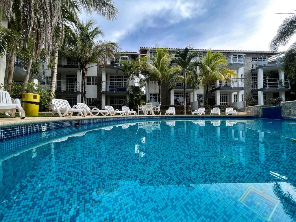 a large swimming pool with chairs and palm trees at Blue Palm - Isla de Margarita in Paraguachi