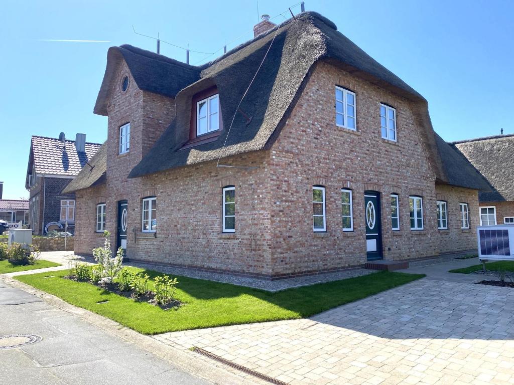 a large brick building with a thatched roof at Lokelk Lunhüs Hausteil 4 in Oevenum