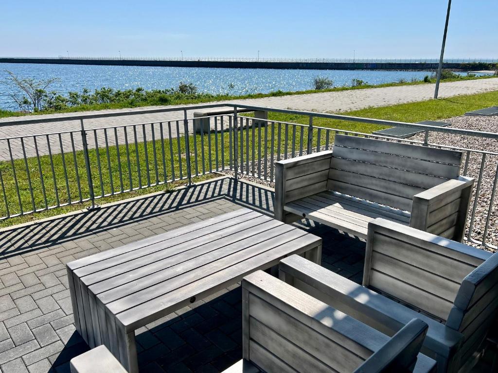 two wooden benches sitting in front of the water at Ferienwohnung eastside App 3 Olpenitz in Olpenitz