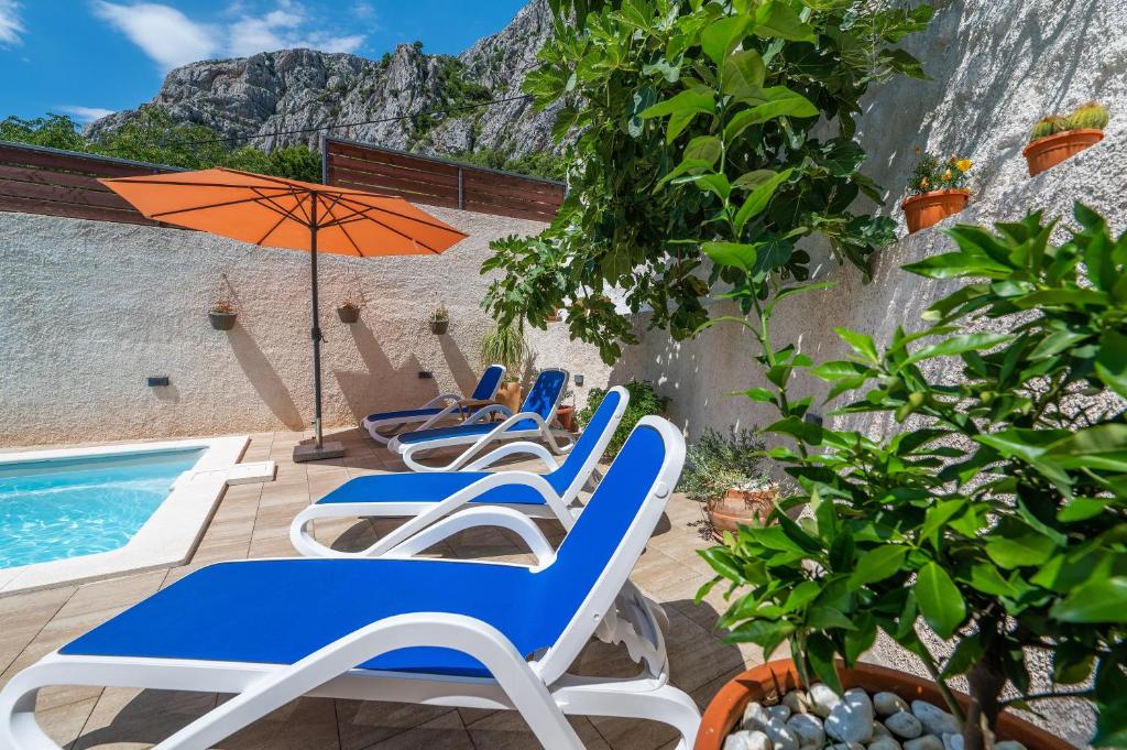 Un grupo de sillas y una sombrilla junto a una piscina. en Apartment Marina on the second floor, en Makarska