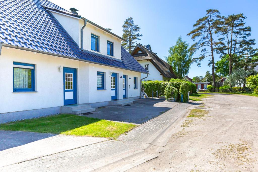a white house with blue doors and a driveway at Ostseeromantik in Neuhaus