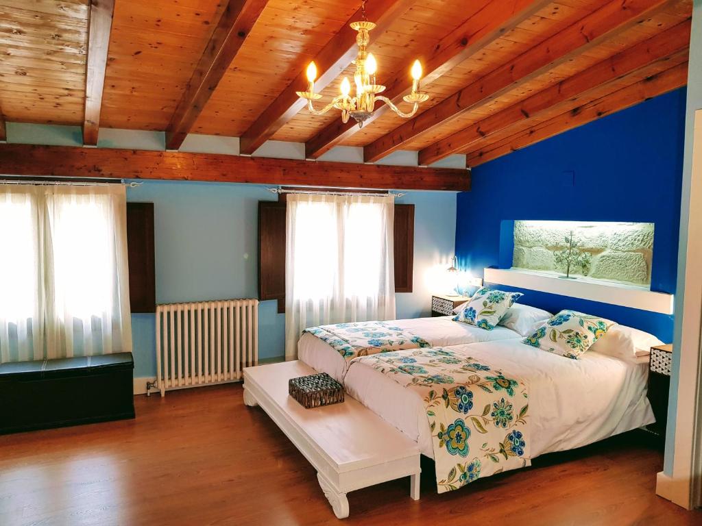 a bedroom with a large bed with blue walls and wooden ceilings at Casa Rural Los Carros in San Asensio