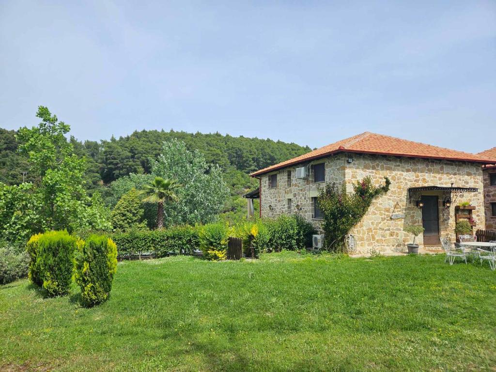 a stone house in a field with a yard at Stone Villas in Nea Roda