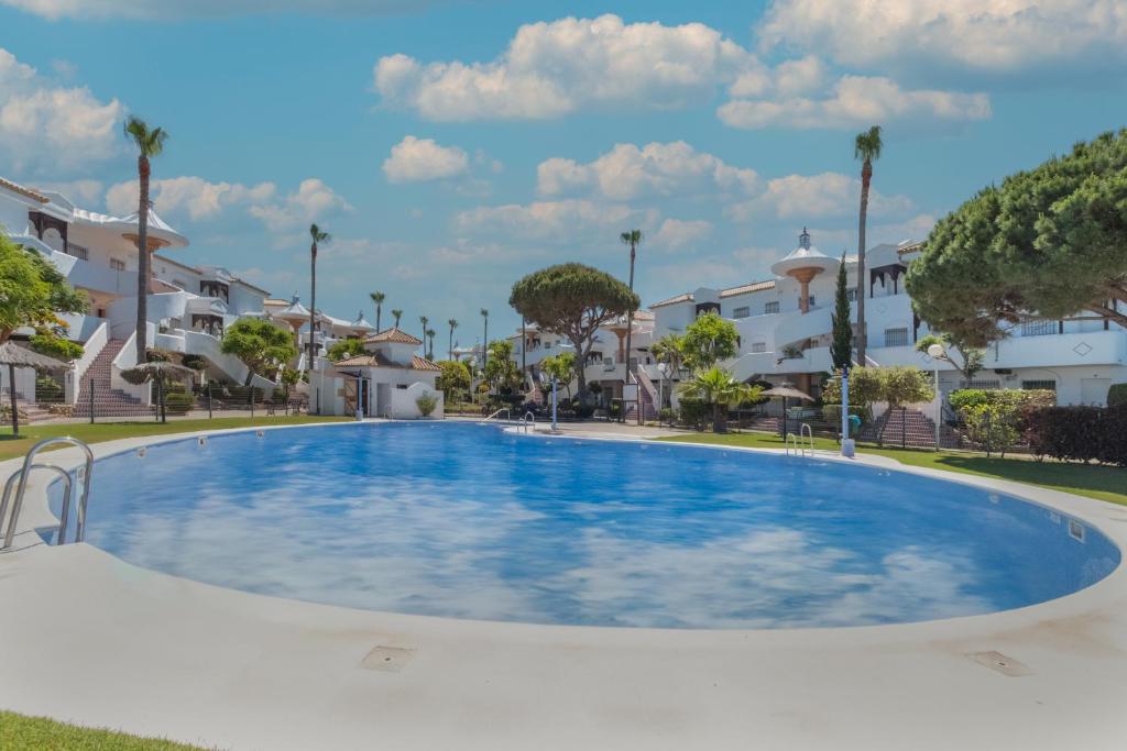 a large swimming pool in a residential area with houses at Ático en Novo Sancti Petri in Chiclana de la Frontera