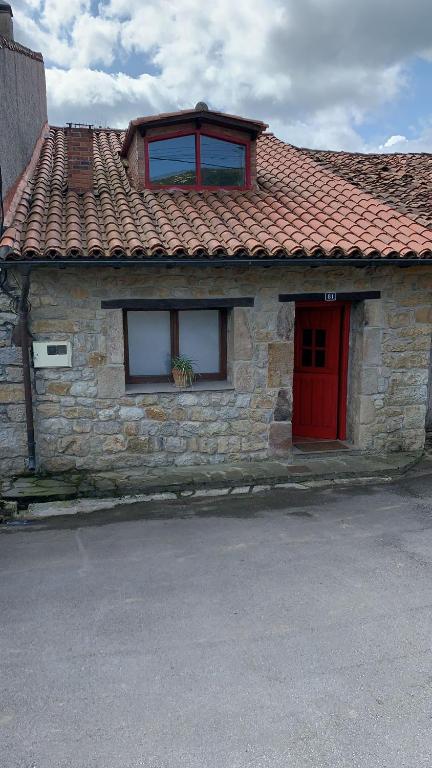 a stone house with a red door and windows at La Casina de Lucia in Merodio