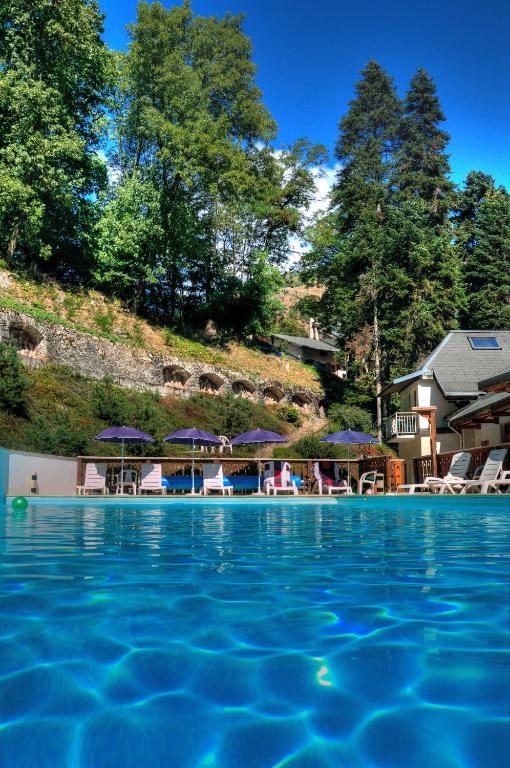 - une piscine avec des chaises et des parasols dans un complexe dans l'établissement Hotel Les Chalets, à Brides-les-Bains