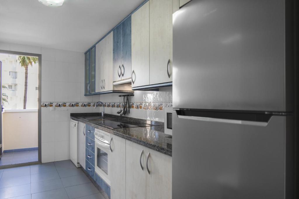 a kitchen with white cabinets and a refrigerator at Apartamentos Hipocampos Calpe Rent Apart in Calpe
