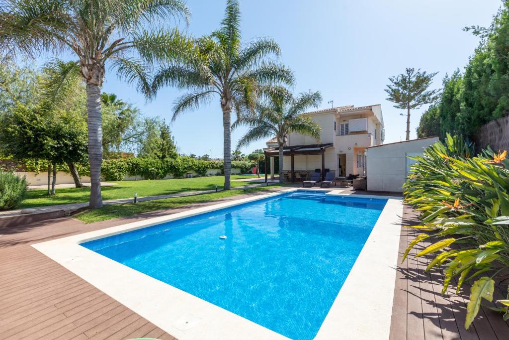 a swimming pool in the backyard of a house with palm trees at Casa junto al mar con jardín in Sagunto