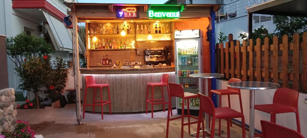 un bar avec des tabourets rouges devant lui dans l'établissement Hotel Villa Ruci, à Ksamil