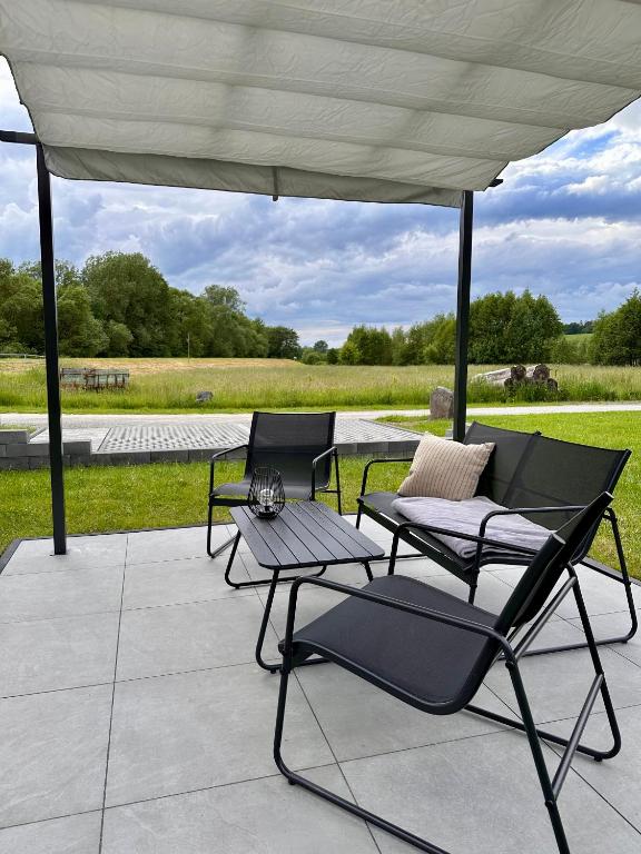 a patio with two chairs and a table under a canopy at Ferienwohnung Storchennest in Eisfeld