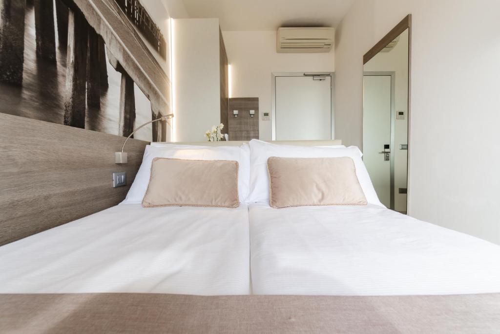 a large white bed with two pillows on it at Hotel Lux in Caorle