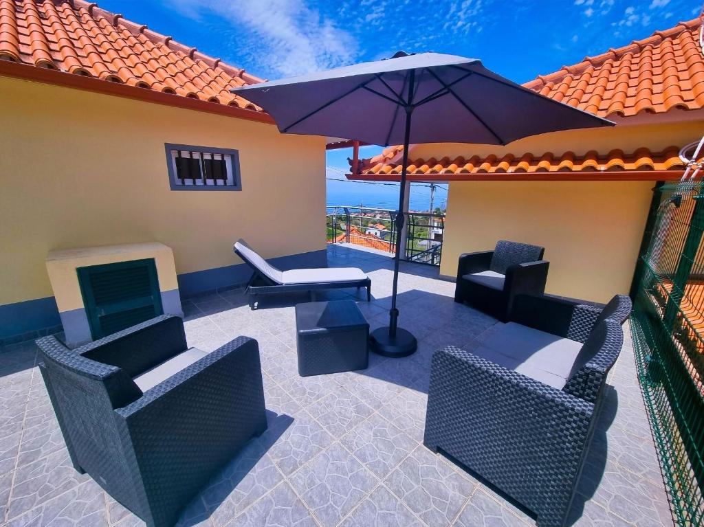 une terrasse avec des chaises, une table et un parasol dans l'établissement Casa en centro de Santana con vista al mar y la montaña, à Santana