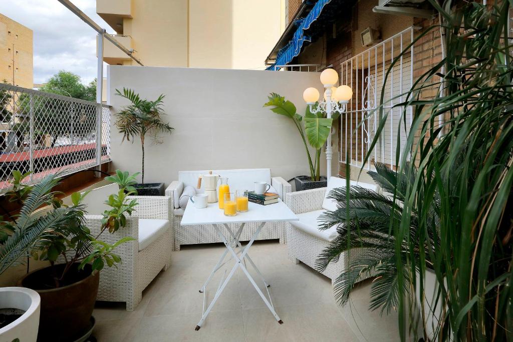 uma varanda com mesa, cadeiras e plantas em Apartamento Jardín Cerca del Centro em Sevilha