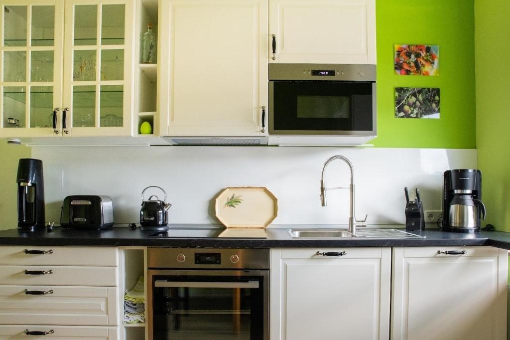 a kitchen with white cabinets and green walls at farbenfrohe Ferienwohnung in Detmold