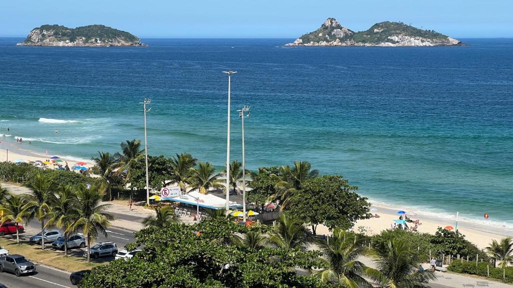 vistas a una playa con palmeras y al océano en Vista para o mar Barra da tijuca, en Río de Janeiro