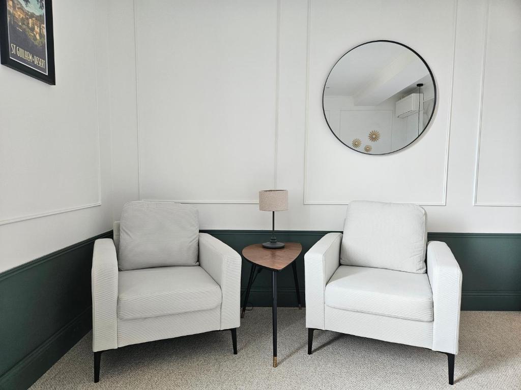 Duas cadeiras e uma mesa num quarto com um espelho em La Suite Gignac em Gignac