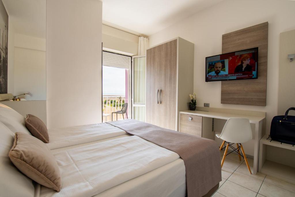 a bedroom with a bed and a desk and a window at Hotel Lux in Caorle