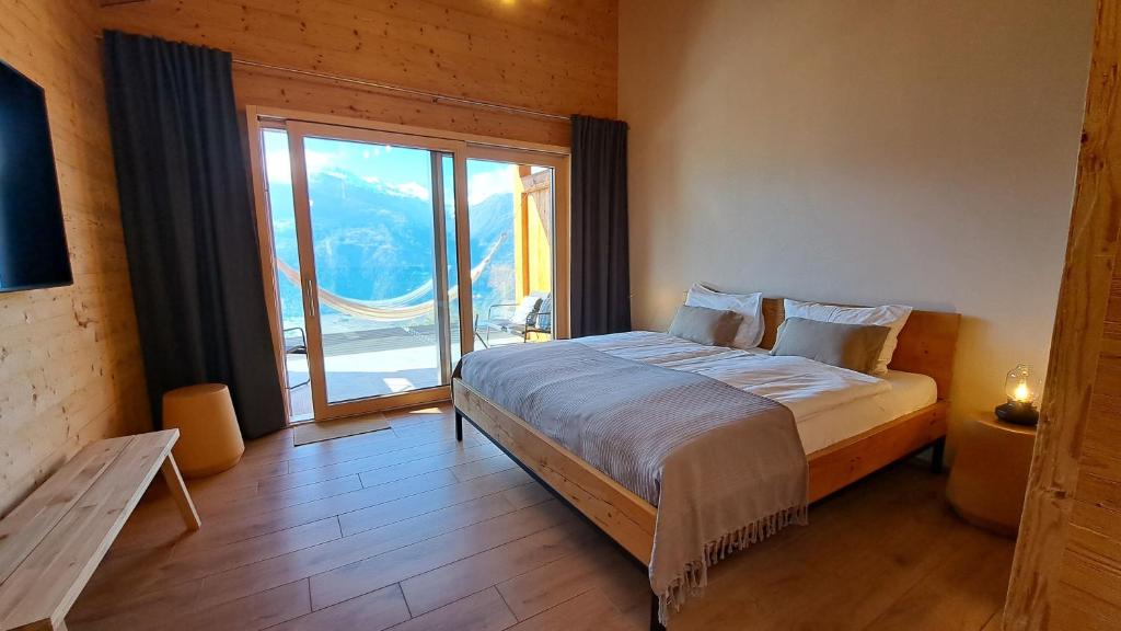a bedroom with a large bed and a large window at Chalet Diognysos B&B, Boutique Hotel & Wellness in Crans-Montana