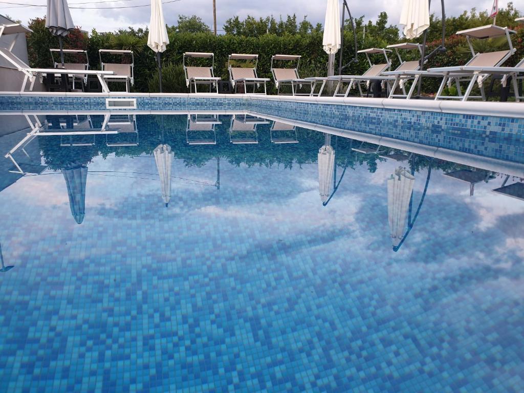 una piscina de agua azul con sillas y sombrillas en Apartments Lea with pool, en Malinska